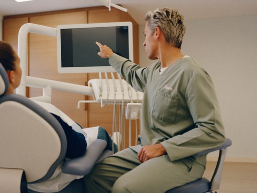 A Wahroonga Dental Group dentist pointing at a chairside screen while reviewing scans with a patient